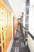 A hallway with wooden doors on the left and tiled walls on the right.