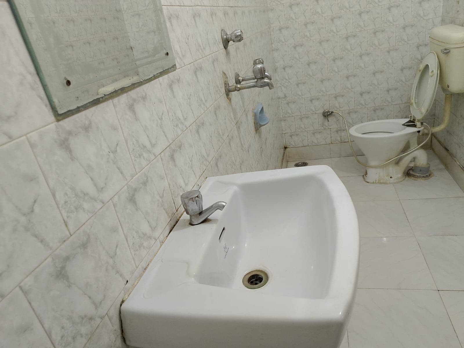 Une salle de bain avec un lavabo blanc, des toilettes et un espace douche.