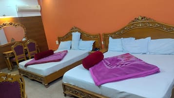 Two double beds with ornate wooden headboards, a wooden desk with a chair, and a mirror on the wall.