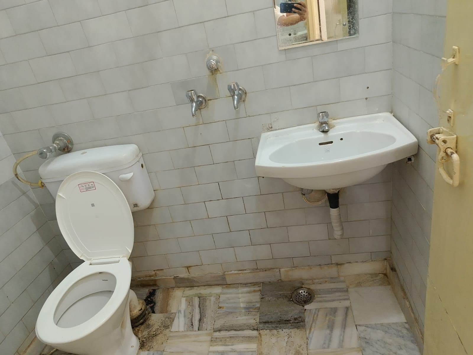 A small bathroom with a toilet, a sink, and a mirror.