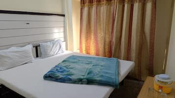 Ein Hotelzimmer mit einem Bett, einem Nachttisch mit Wasserspender und einem Vorhang.