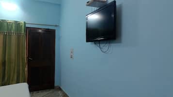 A room with a television mounted on the wall, a wooden door, and a curtain.