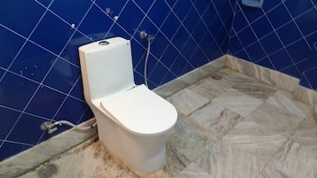 A bathroom with a white toilet, blue tiled walls, and a marble floor.