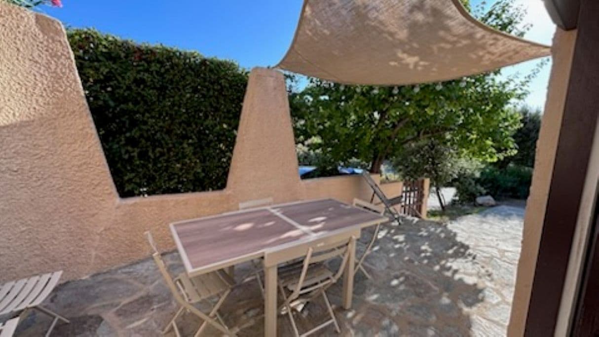 Eine Terrasse im Freien mit Tisch und Stühlen, ein Pavillon spendet Schatten, und ein Boden aus Stein.