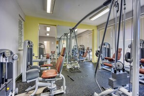 Et fitnesscenter med diverse træningsmaskiner, spejle og en gul væg.