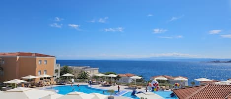 A resort with multiple swimming pools, lounge areas, and a view of the sea.