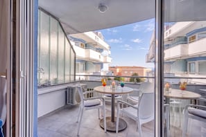 A balcony with a table and chairs, air conditioning units, and a view of neighboring buildings. - Residence Skiper Savudrija Apt 153 Pool & Gym (Umag)