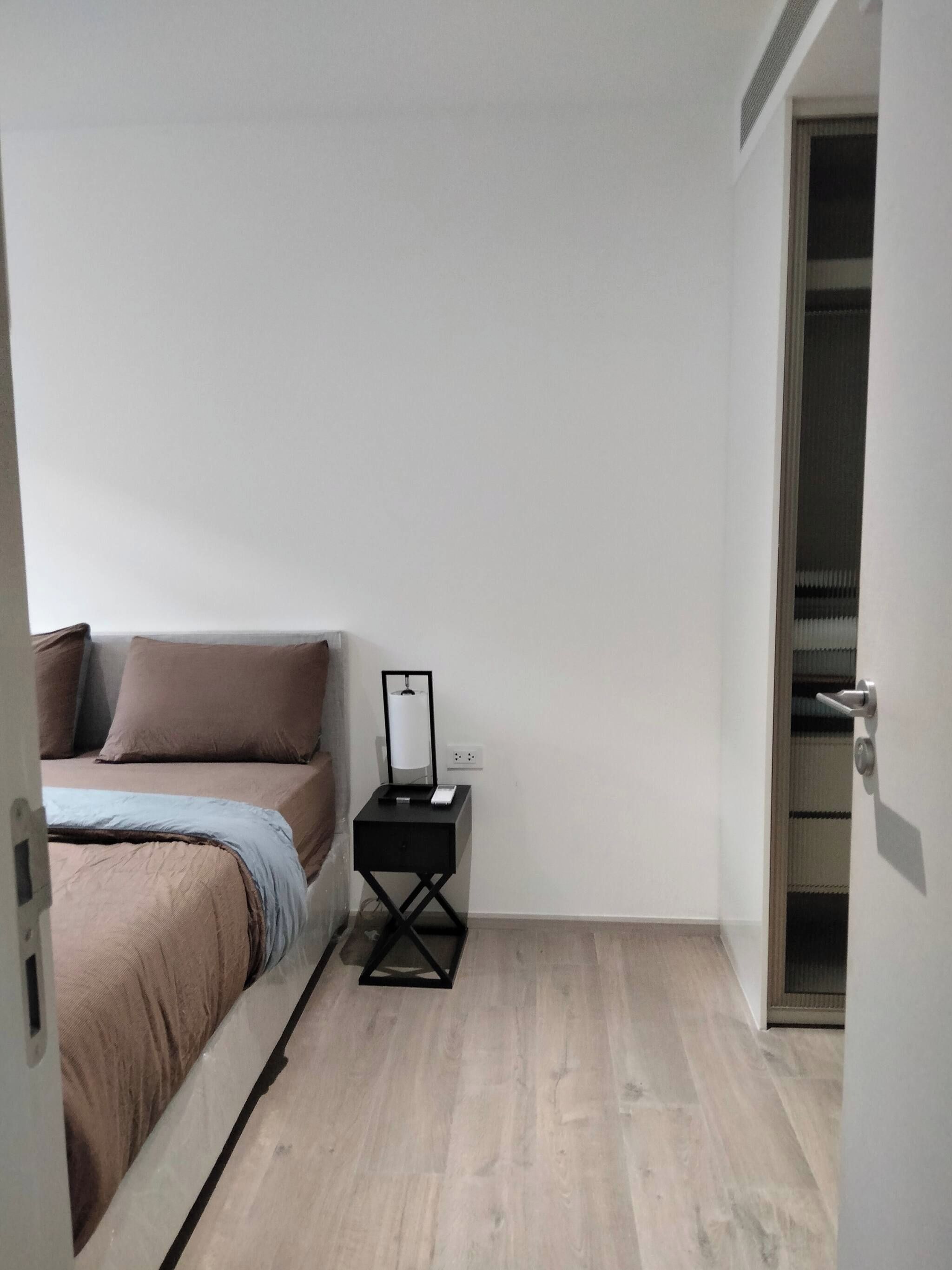 A bedroom with a bed, bedside table, and a wardrobe.