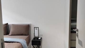 A bedroom with a bed, bedside table, and a wardrobe.