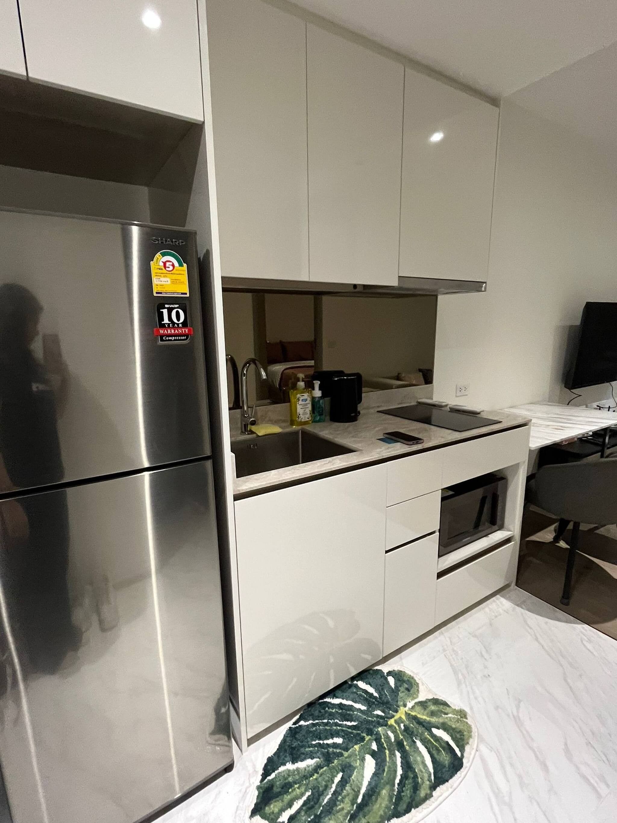 A modern kitchen with a stainless steel refrigerator, a sink, and a microwave.