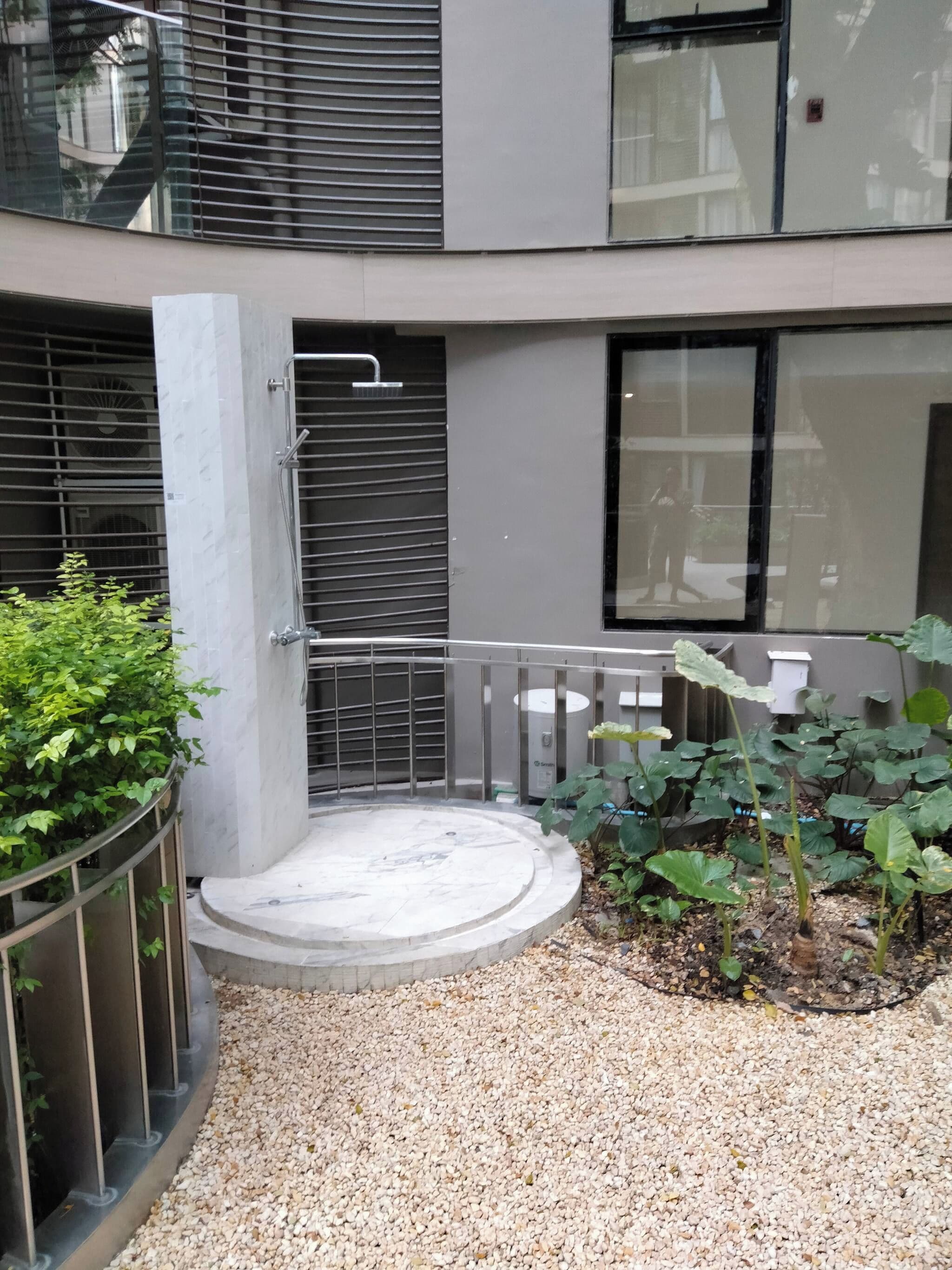 Une cour avec un espace de repos circulaire, une rambarde en métal et un élément décoratif aquatique.