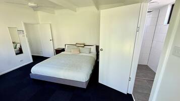 Una camera da letto con un letto, un comodino, uno specchio e una porta che dà su un bagno.