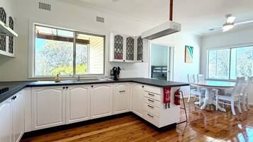 Una cocina con armarios blancos, encimera negra y suelo de madera.