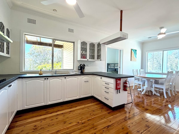 A kitchen with white cabinets, a black countertop, and wooden flooring.