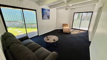A modern living room with a sectional sofa, a round coffee table, a beige armchair, and a painting on the wall.