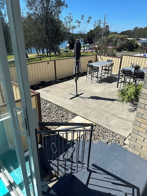 An outdoor patio area with a table and chairs, a covered seating area, and a view of a body of water.