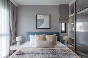 A modern hotel room with a bed, bedside lamps, a large abstract painting, and a wardrobe. - Bang Tao - 4 Beds for Families (Choeng Thale)