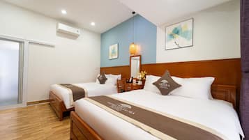 Quarto de hotel com duas camas, cabeceira de madeira, mesa de cabeceira, espelho e ar condicionado fixado na parede.