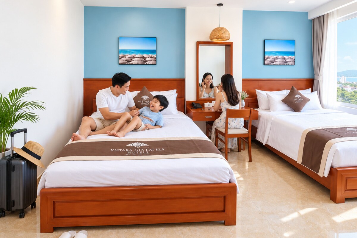 Quarto de hotel com cama, escrivaninha, cadeira, mala e planta.