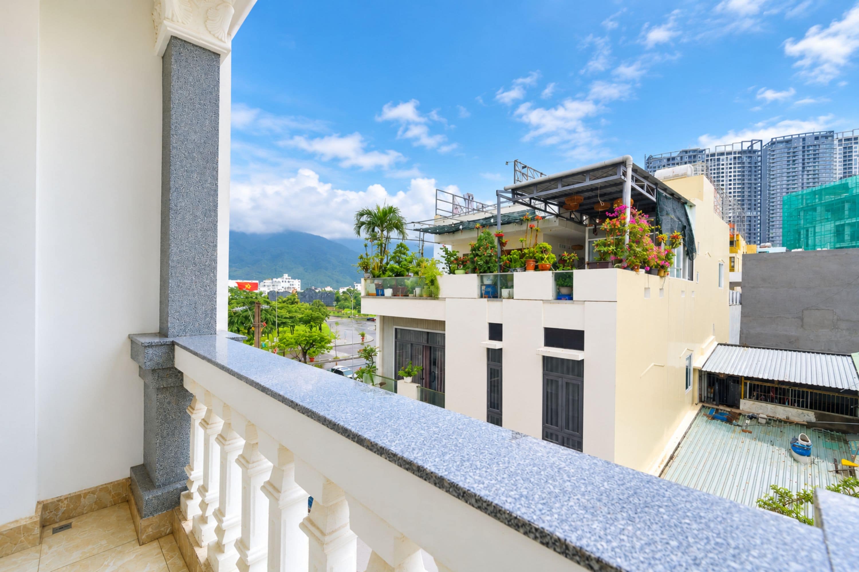 Un balcon offrant une vue sur le paysage urbain, avec des bâtiments et une montagne visible au loin.