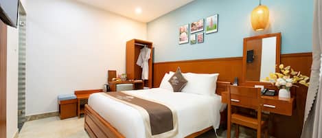 Habitación de hotel con cama, mesita de noche, escritorio, silla, armario y espejo.