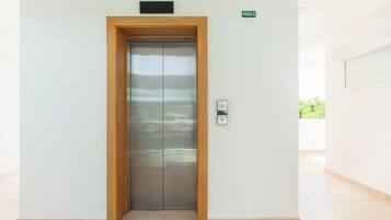 Um elevador moderno com estrutura de madeira, visor digital e campainha.