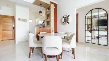 Un comedor moderno con una mesa redonda y cuatro sillas, una cocina con armarios de madera y un gran ventanal arqueado.