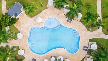 Vista aérea de uma piscina rodeada por palmeiras e espreguiçadeiras.