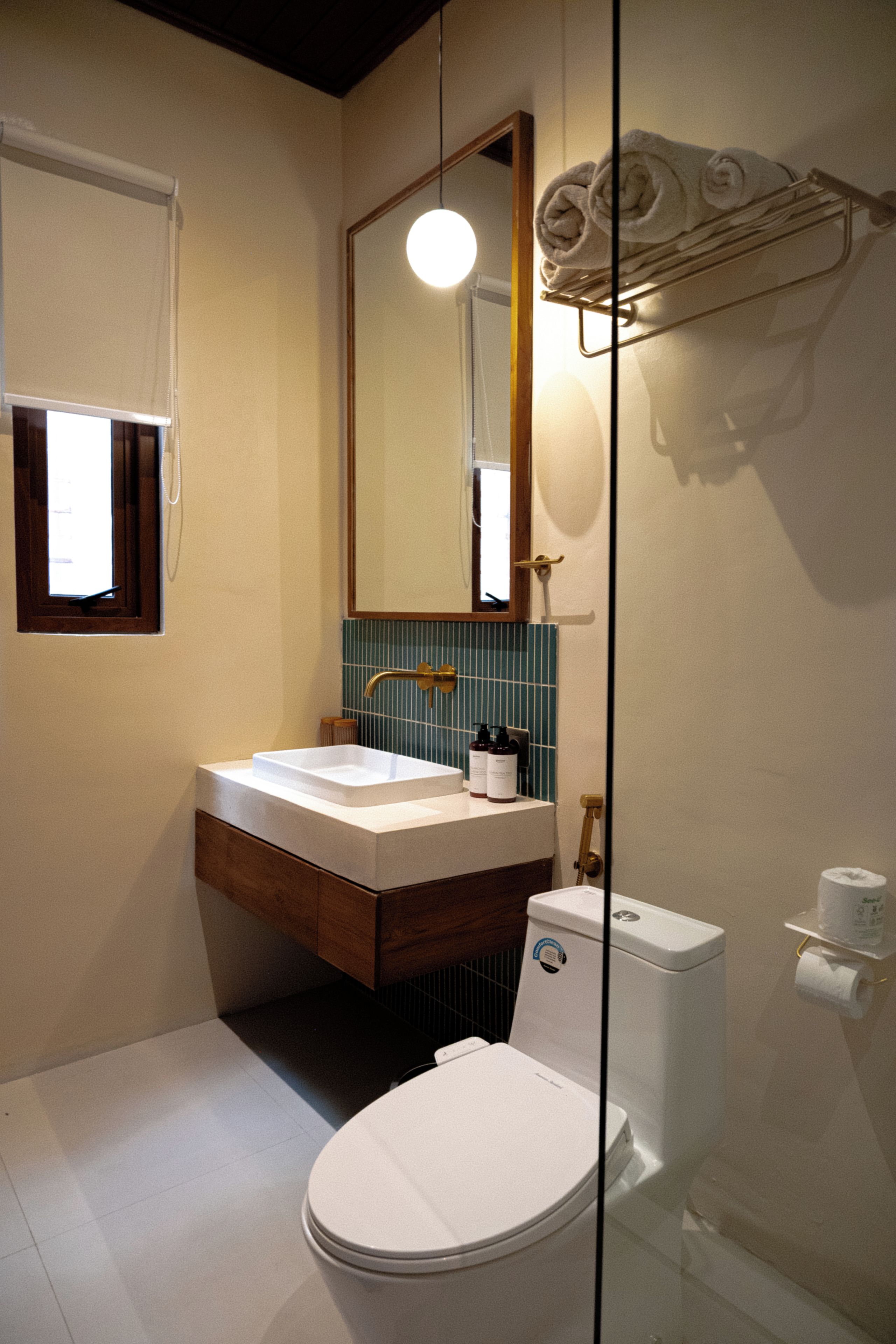 Ein Badezimmer mit weißem Waschbecken, einem Spiegel, einer Toilette und einem Handtuchhalter.
