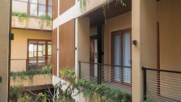 A multi-level residential building with balconies, wooden railings, and some greenery.