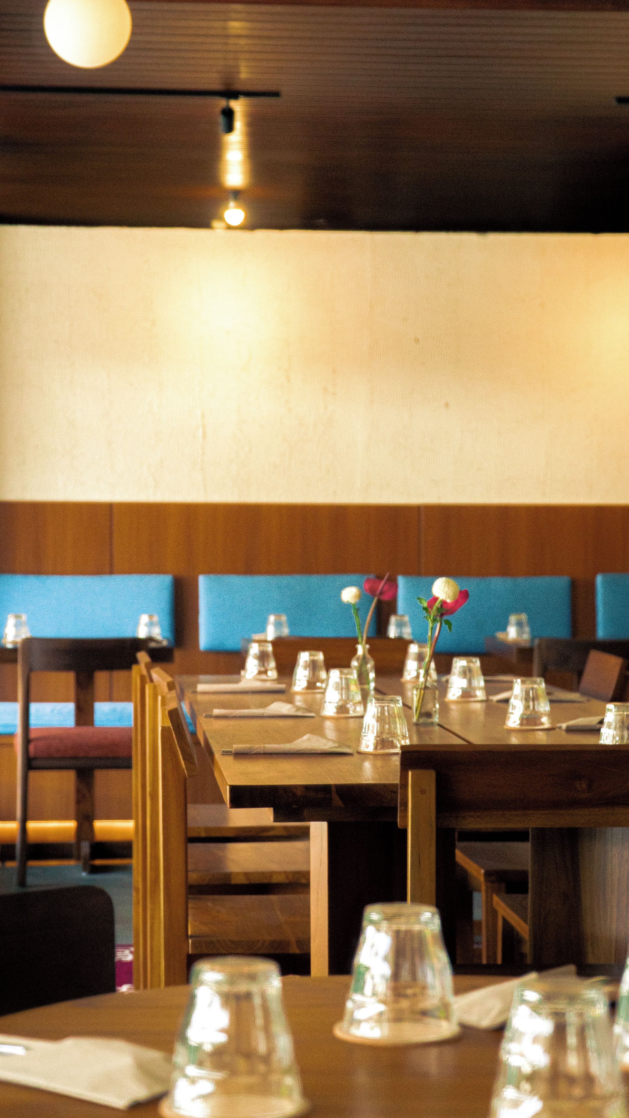 A restaurant interior with wooden tables, chairs, and blue cushioned booths.