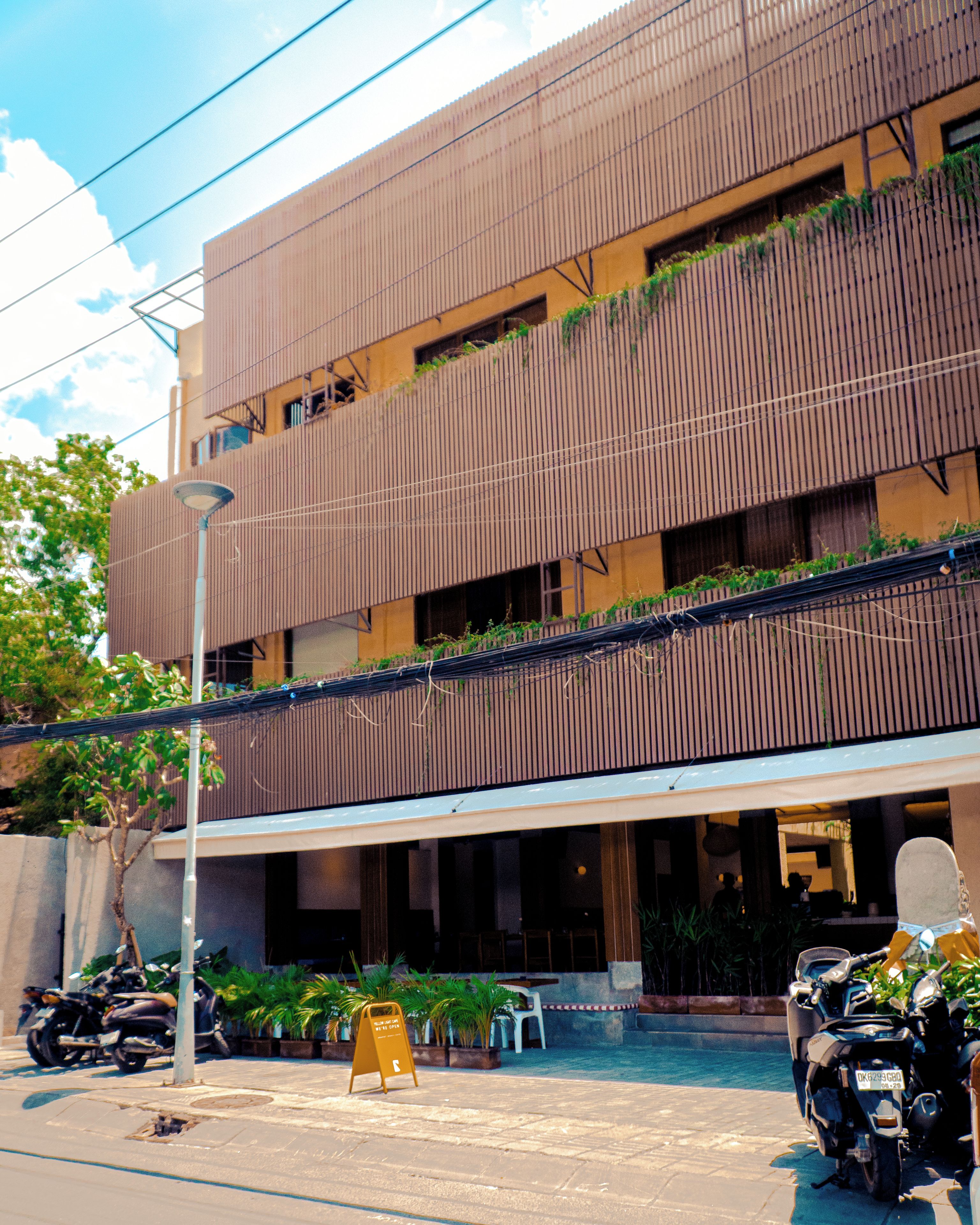 Un edificio de varios pisos con un diseño moderno, con balcones y una zona de estar exterior techada.