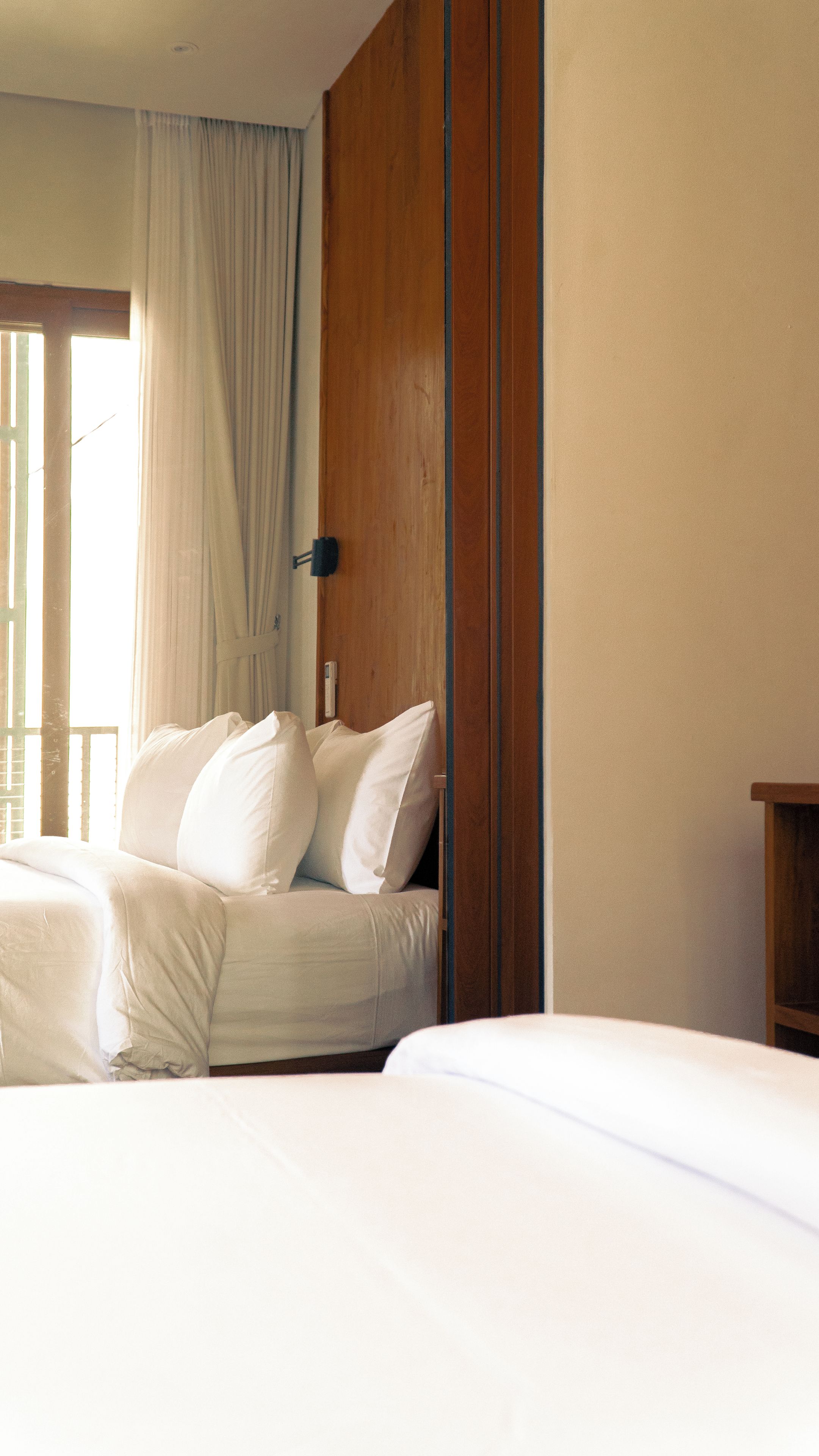 Una habitación de hotel con una cama, un armario de madera y una ventana con cortinas.