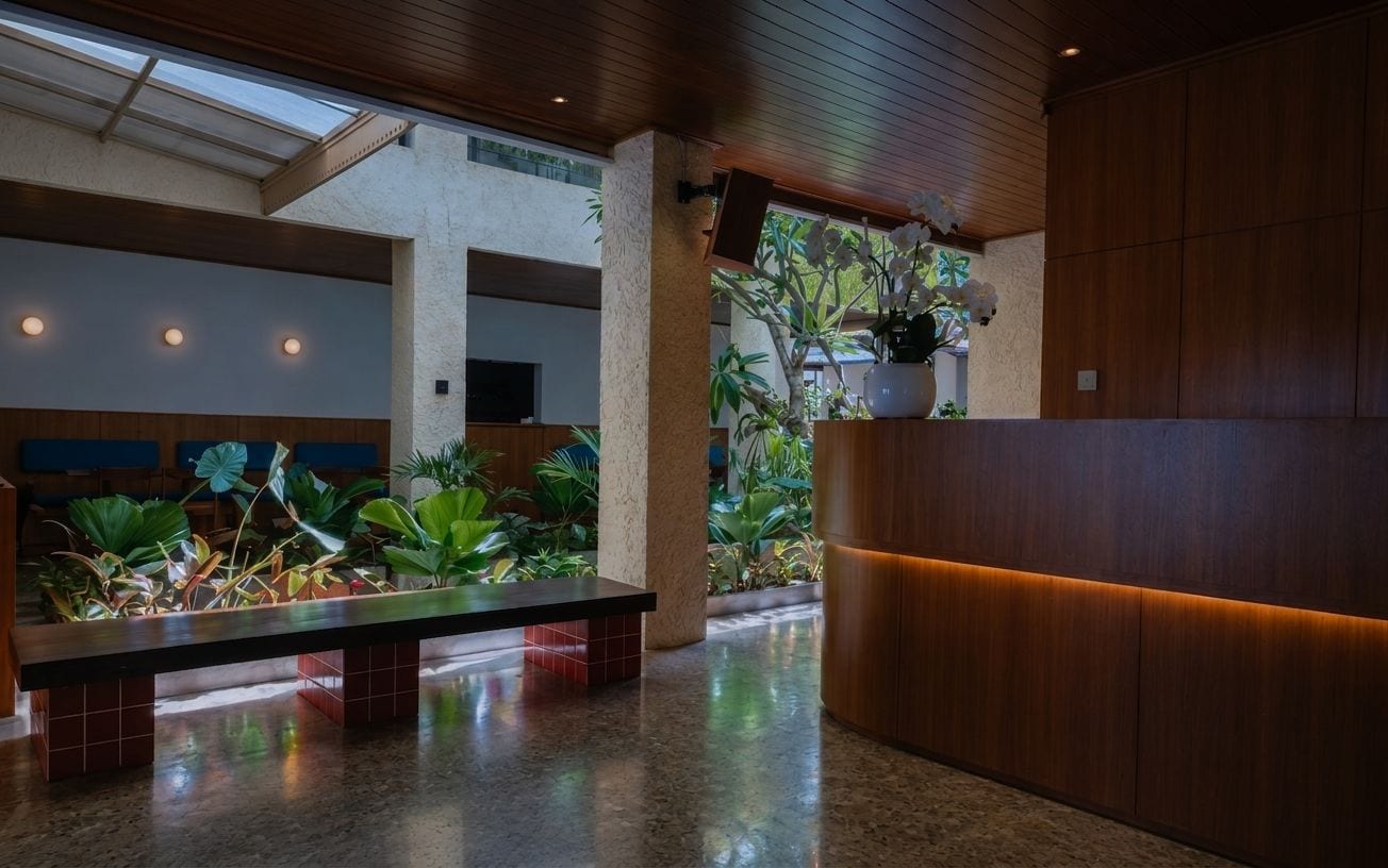A lobby with a reception desk, seating area, and a large window allowing natural light.