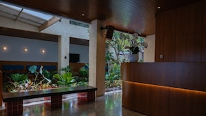 A lobby with a reception desk, seating area, and a large window allowing natural light.