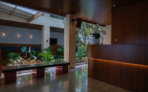A lobby with a reception desk, seating area, and a large window allowing natural light.