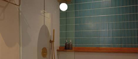 Un baño con inodoro blanco, ducha con cerramiento de vidrio y pared de azulejos.