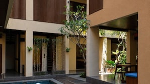 A modern building with a swimming pool, wooden slatted balconies, and indoor plants.