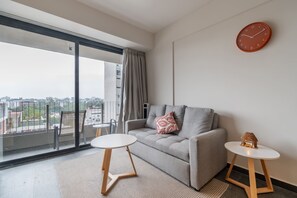 Ein modernes Wohnzimmer mit einem grauen Sofa, einem kleinen runden Tisch und einem dekorativen Gegenstand an der Wand.