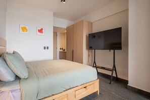 A bedroom with a bed, a TV on a stand, and two framed pictures on the wall. - Girasol - Loft Aranza c-Balcón Condesa Views (Mexico City)