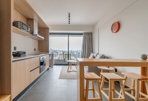 Eine moderne Küche mit Blick auf die Stadt, ein Essbereich mit Hockern und ein großes Fenster mit Vorhängen.