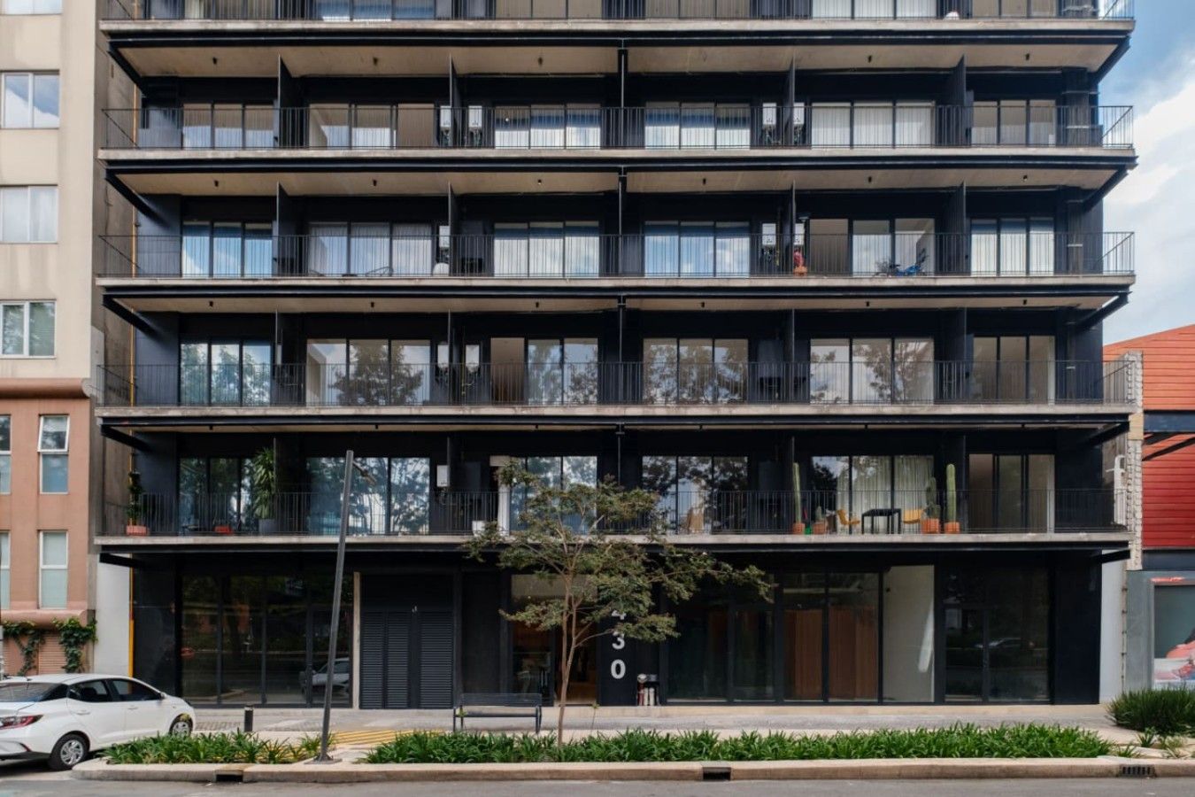 Un immeuble à plusieurs étages, doté de balcons, de grandes fenêtres et d’une entrée bien visible.
