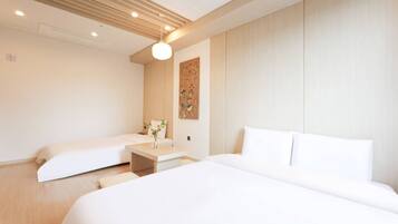 Habitación de hotel con dos camas, una mesita de noche con un florero y una obra de arte colgada en la pared.
