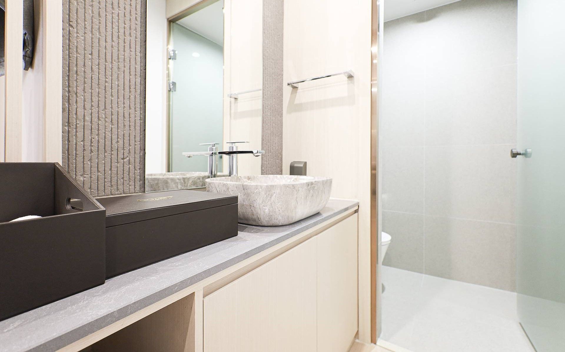 Un baño moderno con un espejo grande, un lavabo sobre encimera y una zona de ducha.