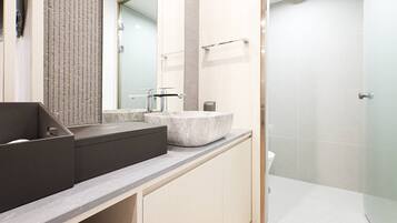 Un baño moderno con un espejo grande, un lavabo sobre encimera y una zona de ducha.