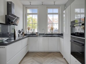 Eine moderne Küche mit weißen Schränken, schwarzen Arbeitsplatten und einem Fischgrätparkett.