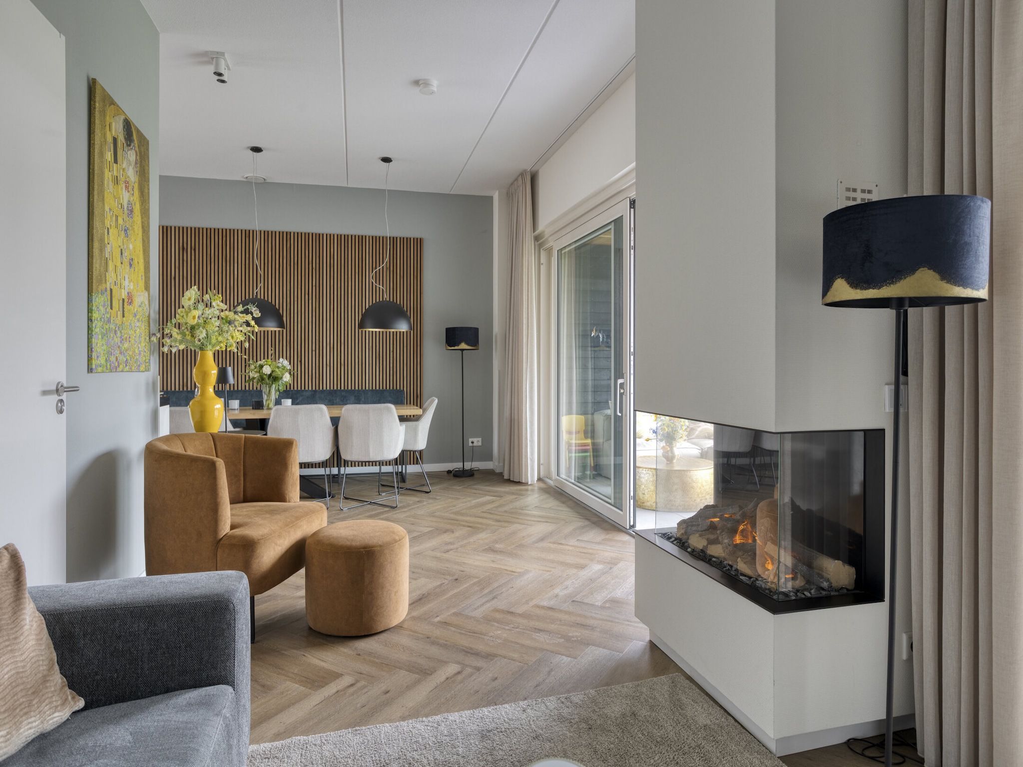 A modern living room with a fireplace, a dining area, and a large window.
