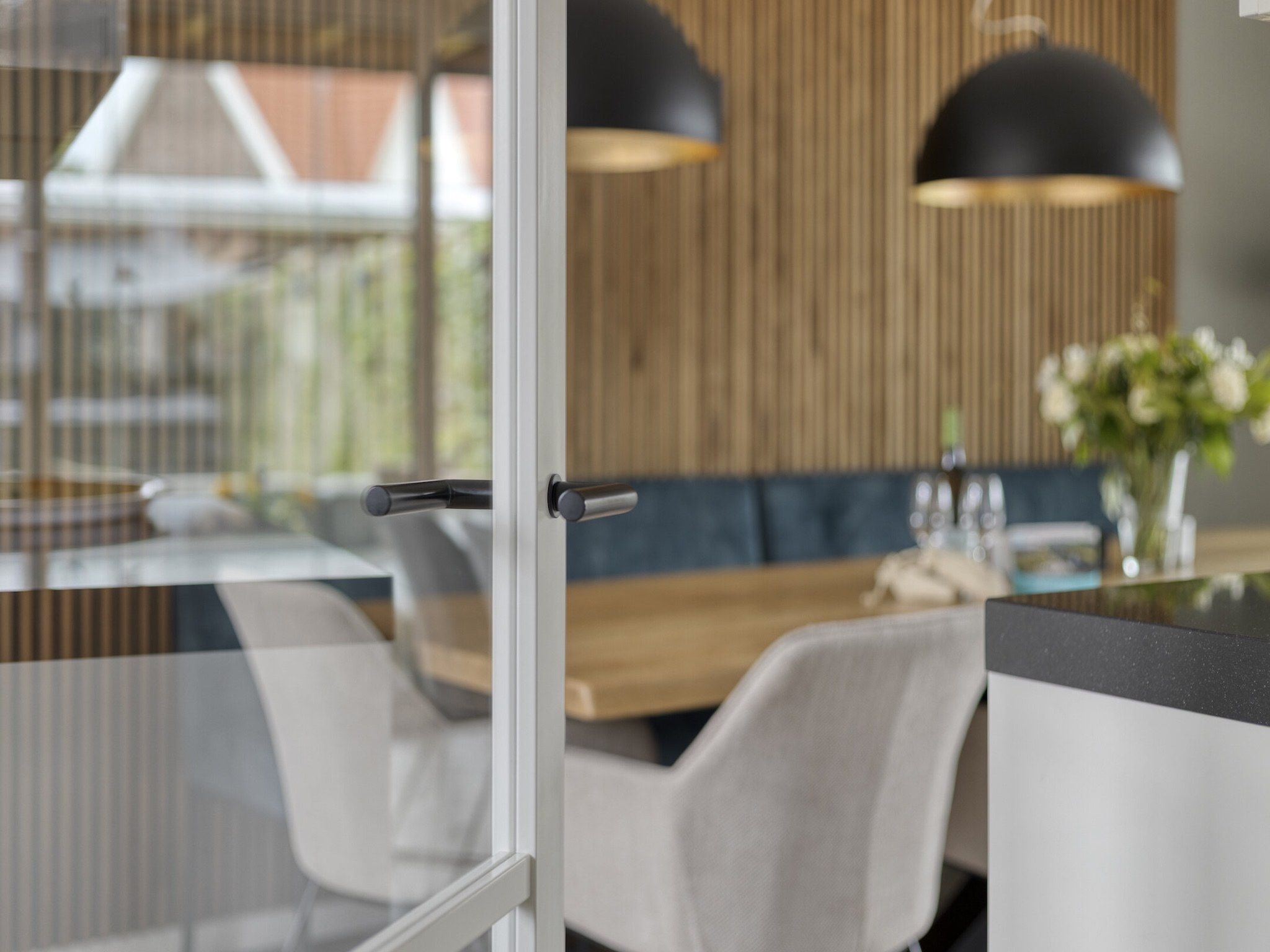 A modern dining area with a glass partition, a wooden wall, and a seating arrangement.