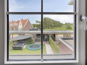 Ein Wohnhaus mit Garten, inklusive Trampolin, Sitzgelegenheit im Freien und einer überdachten Terrasse.