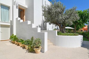 A modern building with a white facade, a staircase leading to an entrance, and a row of potted plants along the front. - El Jabeque 4 pax - Denia, Costa Blanca (Denia)
